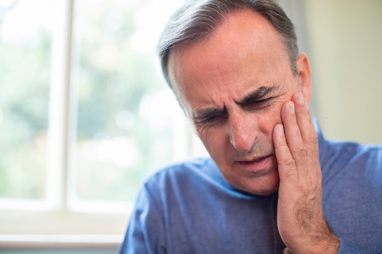 A senior man touching his cheek while in pain due to an endodontic emergency