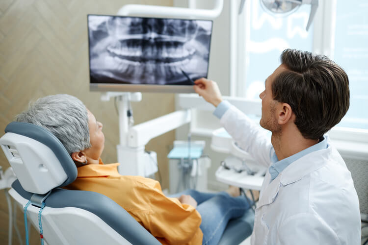 A male endodontist reviewing an x-ray with a female patient before an endodontic retreatment