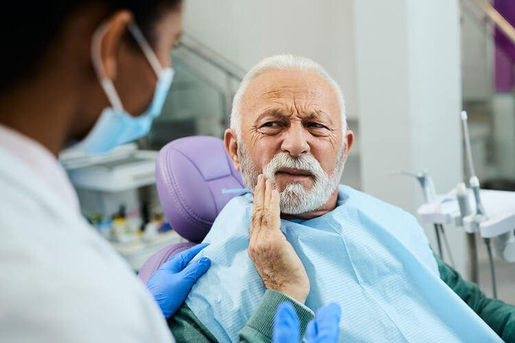 Senior man touching his cheek while in pain before a root canal treatment in Dallas